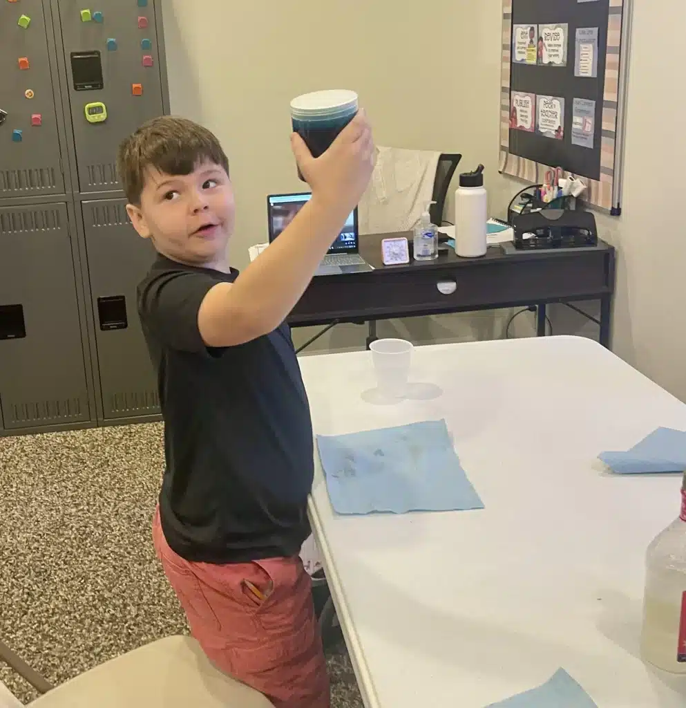 Child holding cup high in class